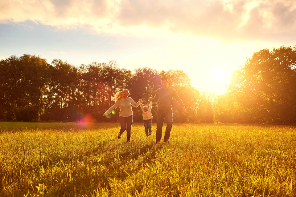 Bonne famille jouant sur l'herbe dans le parc le soir